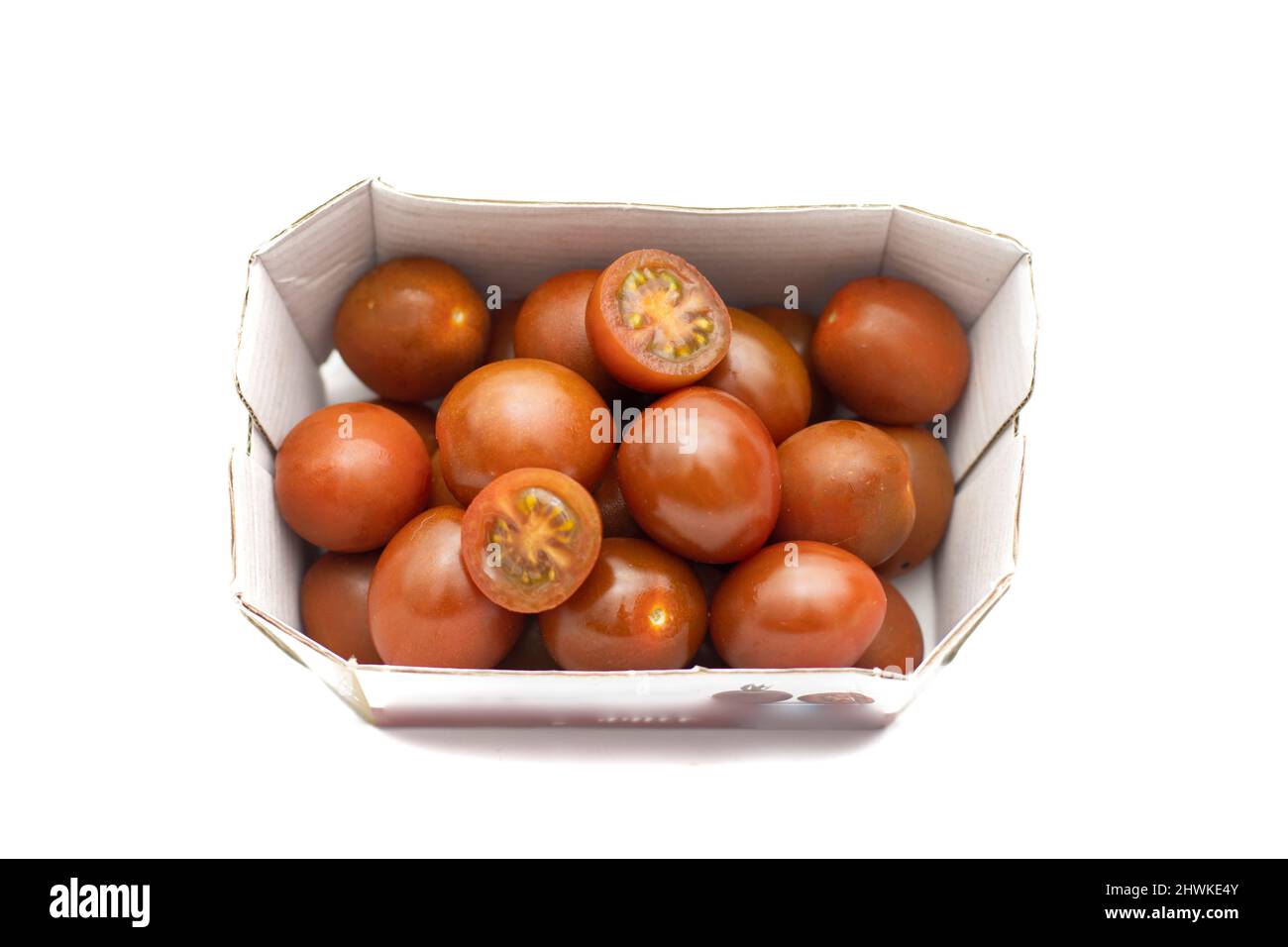 Ein Karton Kirschtomaten, die Mini-Kumato-Sorte. Isoliert auf weißem Hintergrund. Stockfoto