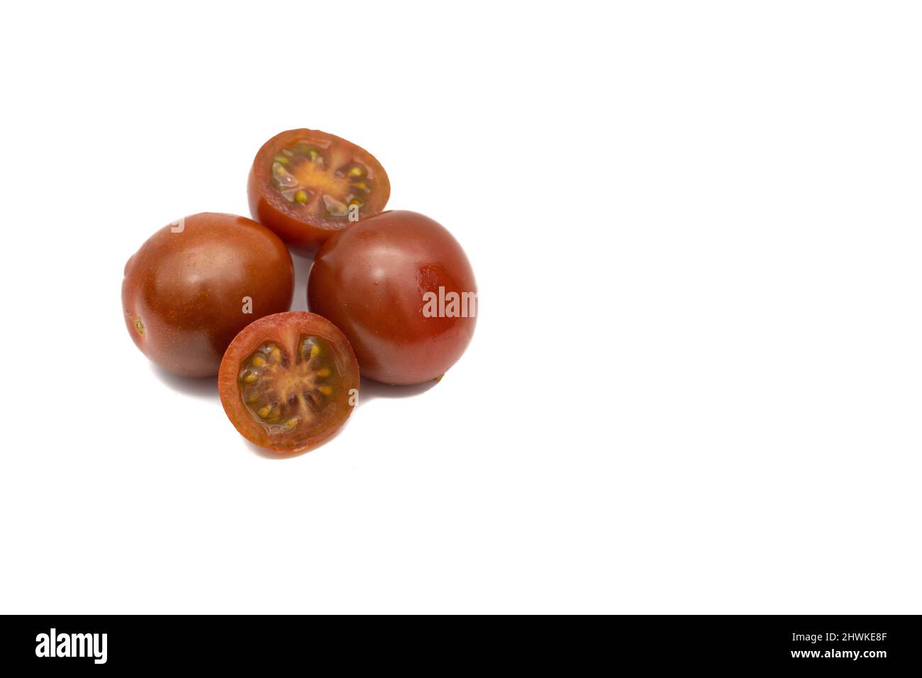 Eine Charge Kirschtomaten, die Mini-Kumato-Sorte. Isoliert auf weißem Hintergrund. Stockfoto