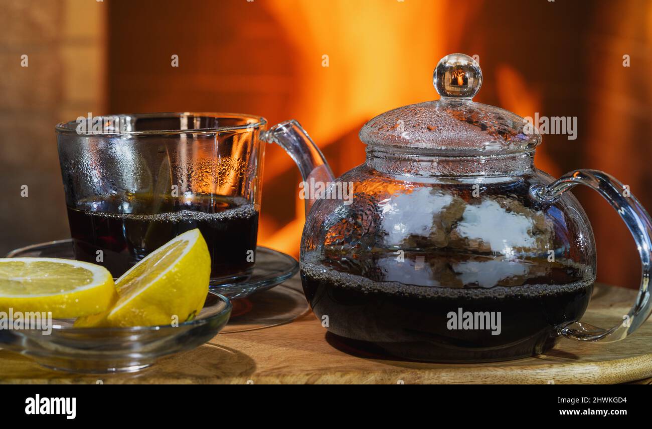 Glas Teekannen und Tasse in der Nähe von gemütlichen Kamin im Landhaus. Stockfoto
