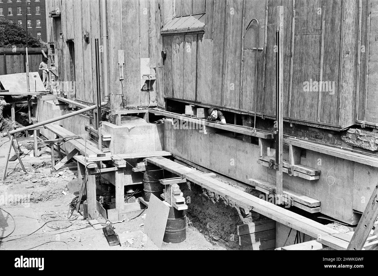 Das Heben der Old Shambles im Zentrum von Manchester beginnt mit einem Aufzug von etwa einem halben Zoll. Ein Ingenieur scheint sich sicher zu sein, dass der Aufzug sicher ist, wenn er aus dem Fundament schaut, um den Fortschritt zu überprüfen. 22.. Juli 1971. Stockfoto