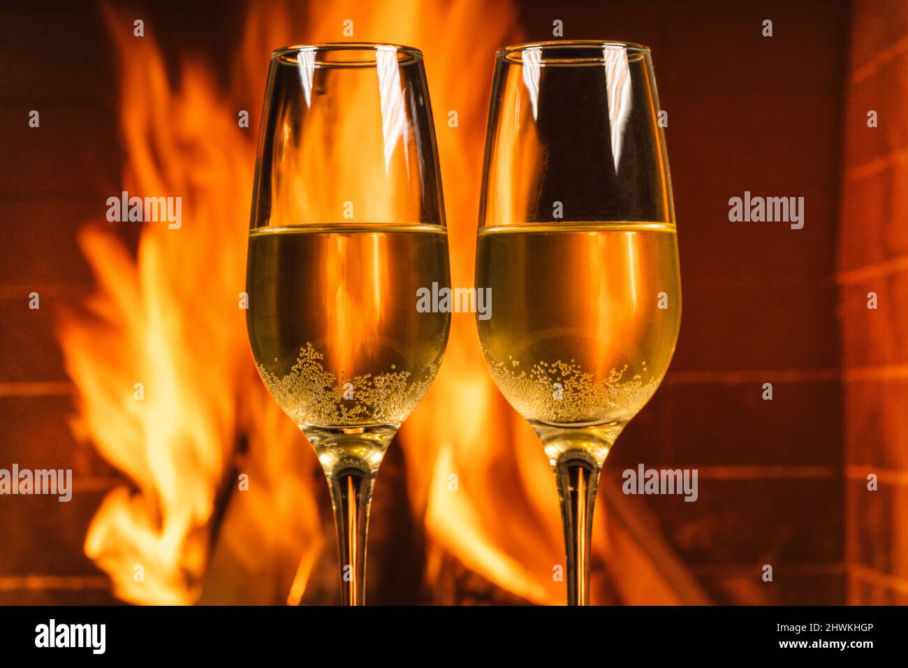 Zwei Gläser Champagner vor einem gemütlichen Kamin in einem Landhaus, aus nächster Nähe. Stockfoto