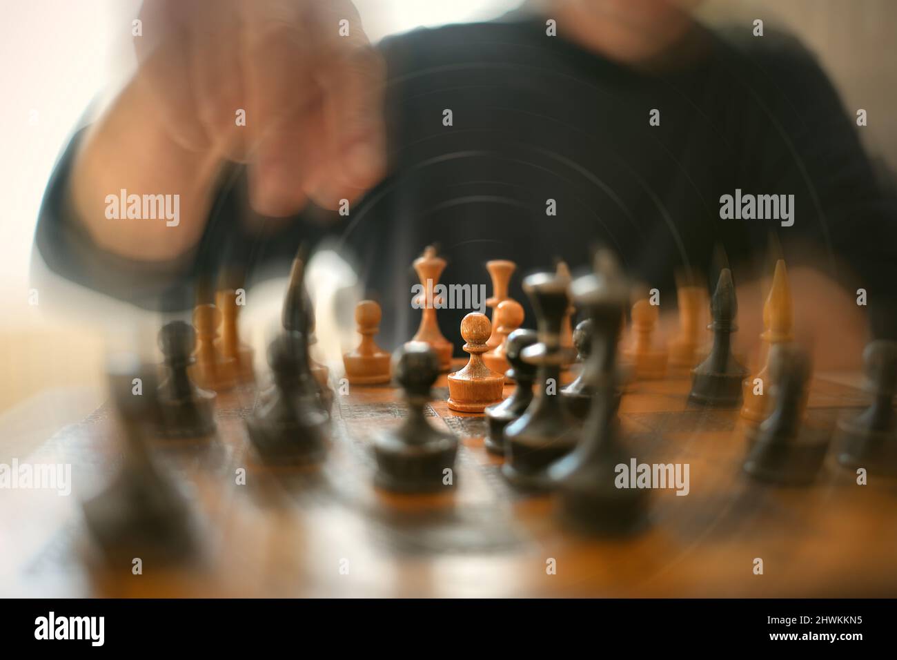 Verschwommene Technik ausgewählter Fokusspieler, der seinen nächsten Schritt auf dem alten Schachbrett spielt. Stockfoto