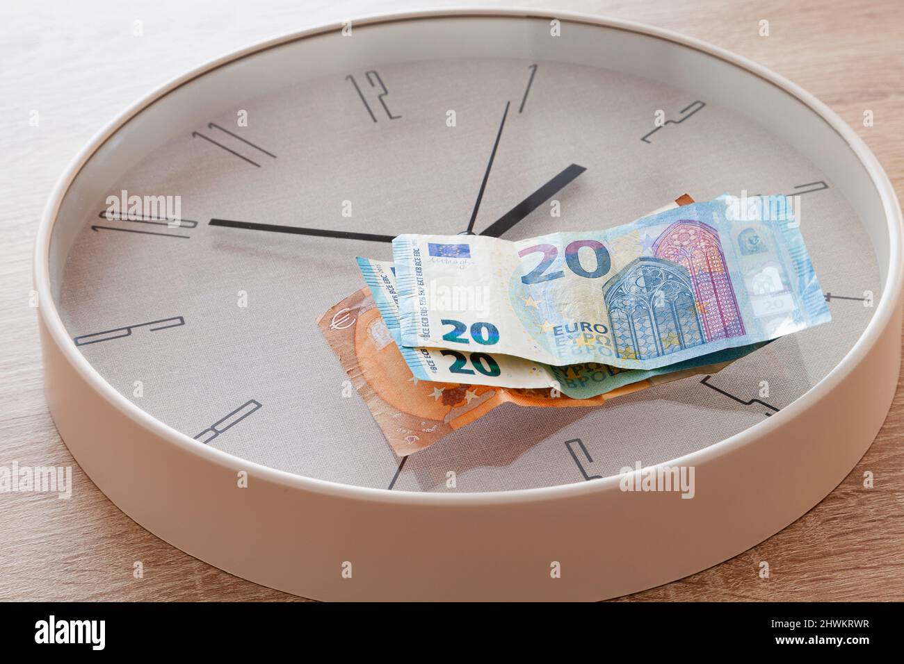 Es gibt zwei 20-Euro-Scheine und eine 50-Euro-Scheine auf einer großen rund-um-die-Uhr-Uhr. Die Uhr schlägt zehn bis zwei. Stockfoto