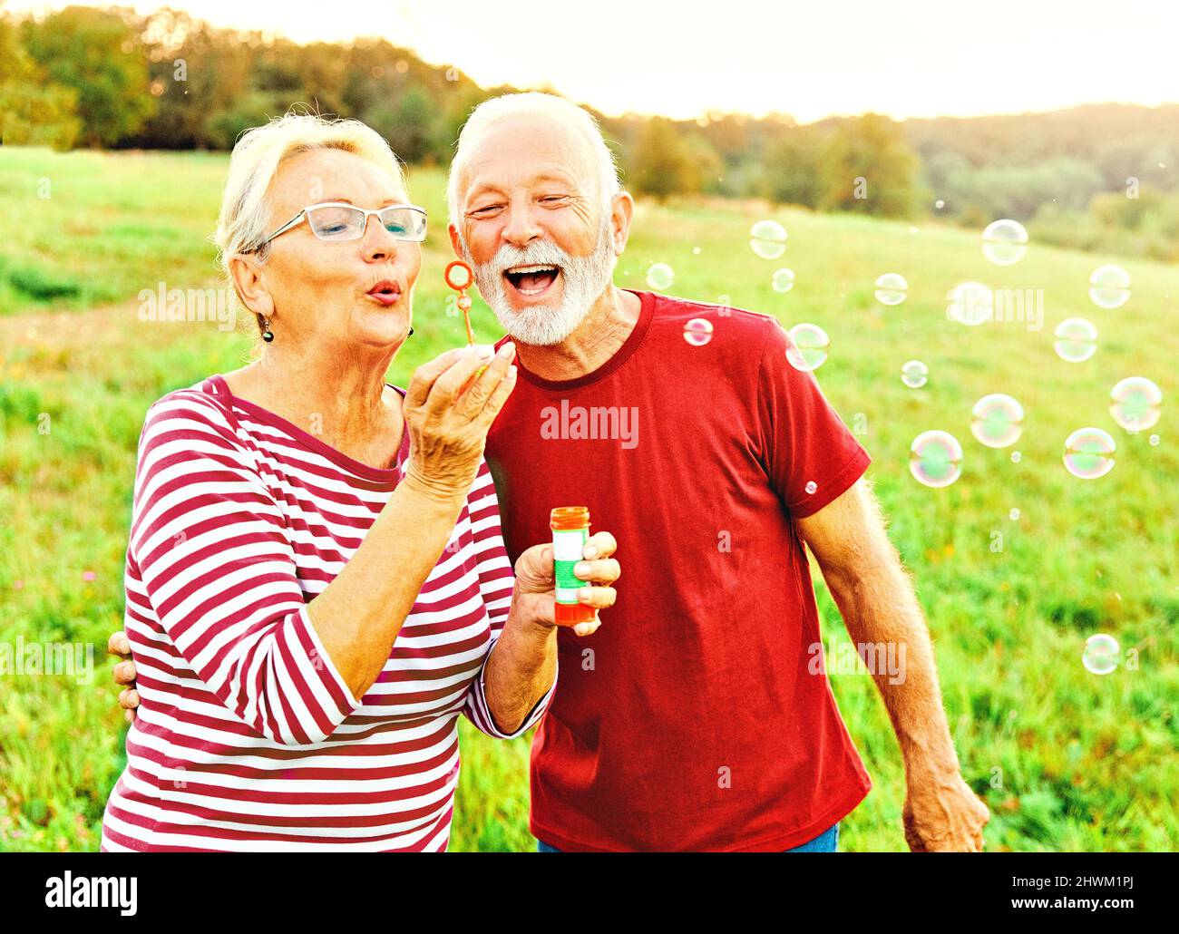 Frau Mann im Freien Senior paar glücklich Spaß Ruhestand zusammen Blase Seife weht Liebe alte Natur reifen Stockfoto