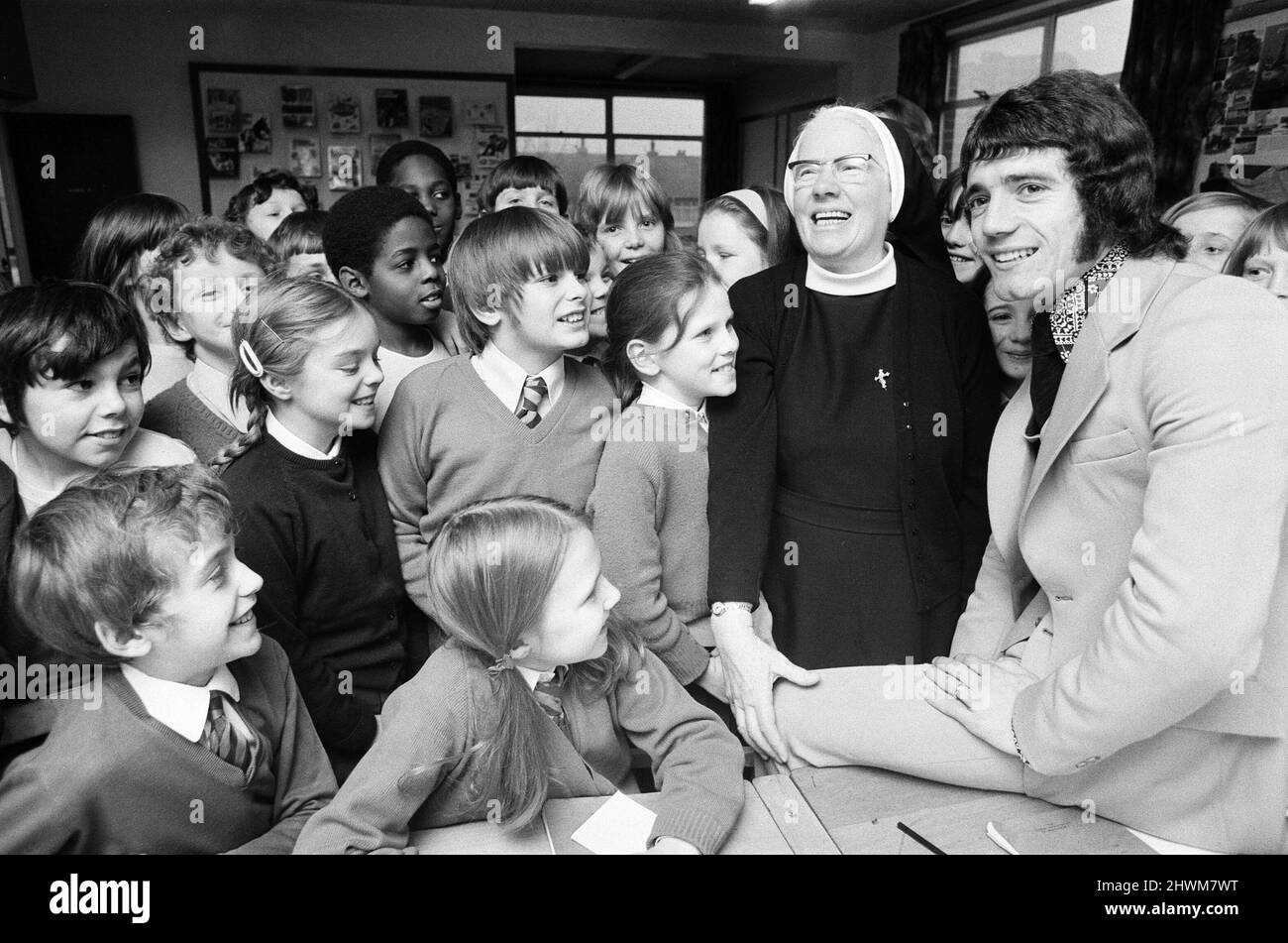 Kevin Keegan, das Fußballidol von England und Liverpool, kehrt an seine alte Schule zurück, die Grundschule von St. Francis Xavier in Doncaster, wo er seine Schulleiterin, Schwester Mary Oliver, trifft. Schwester Mary schrieb vor Jahren in seinem Schulbericht: „Guter Sportler. Kevin muss mit seinem Fußball ermutigt werden.“ Im Bild Kevin Keegan mit Schwester Mary Oliver in einem Klassenzimmer mit Schülern. 8.. Januar 1973. Stockfoto