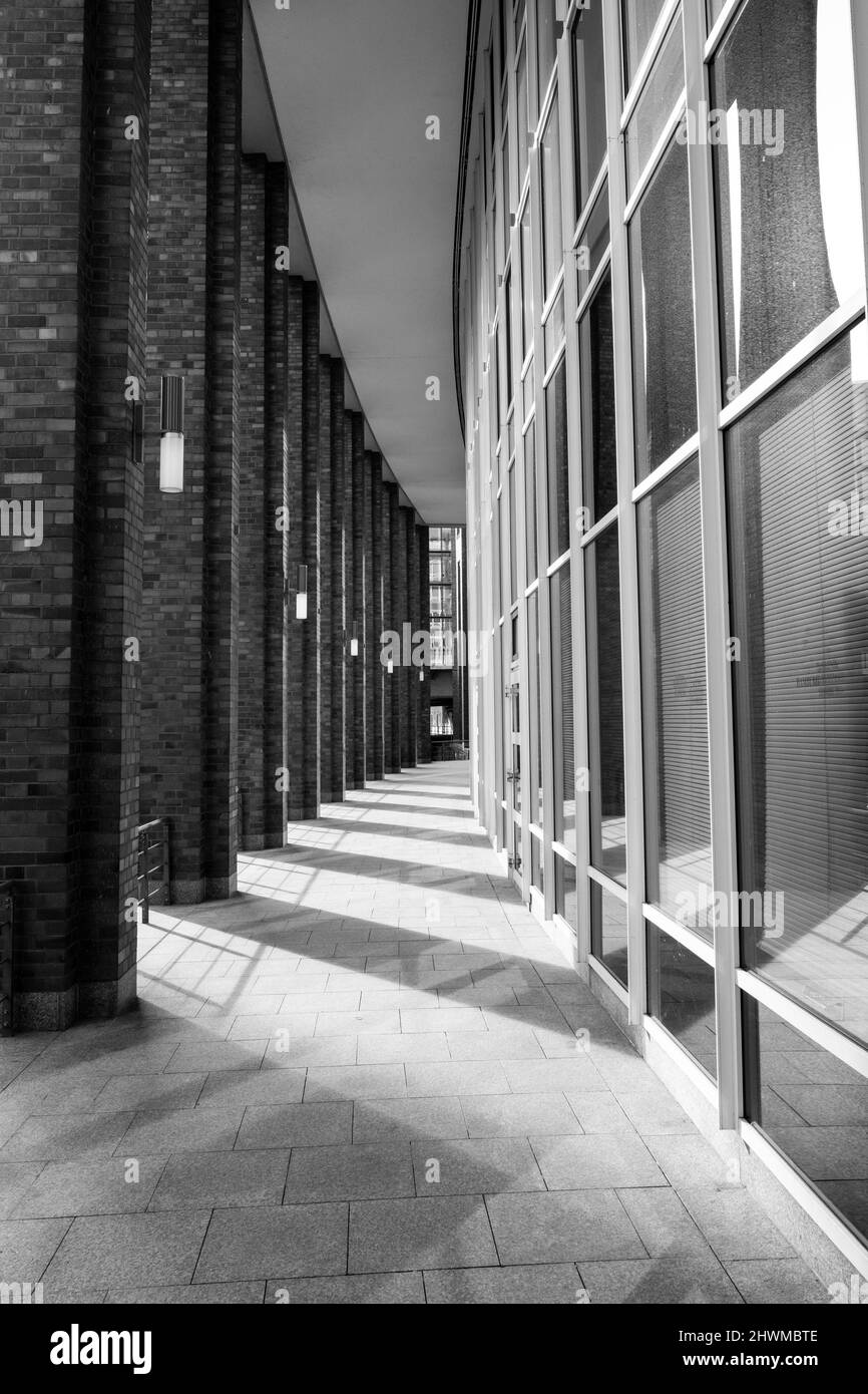 Urbane moderne Straßenfotografie der Hamburger Architektur auf einem geschwungenen Weg zwischen Säulen und Glasfenstern und Schatten auf dem Boden Stockfoto