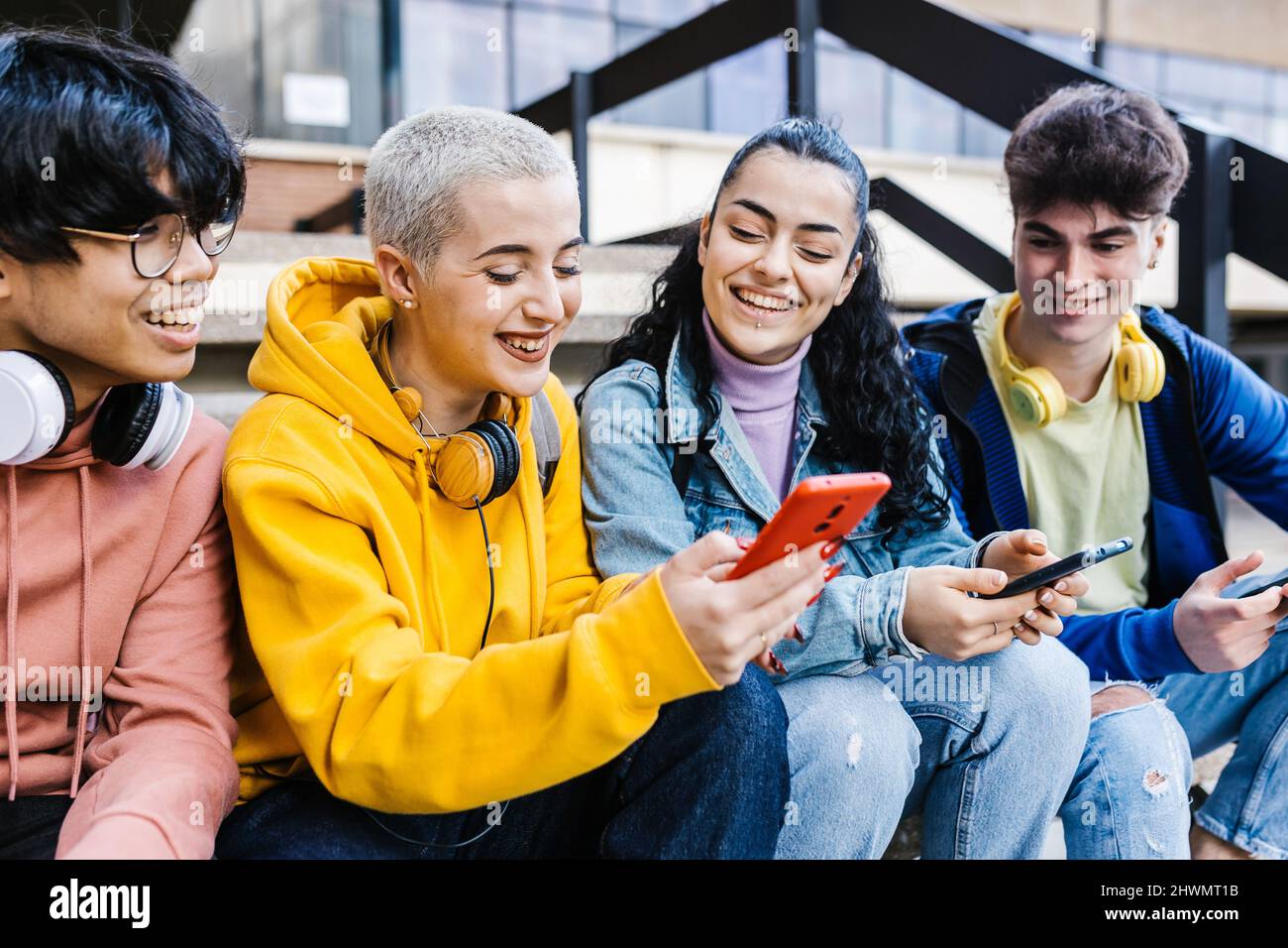 Gruppe von multirassischen Jugendlichen Studenten, die in der Schule Mobiltelefone benutzen Stockfoto