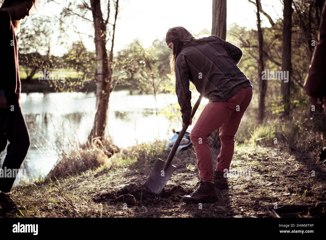Alternative Person gräbt eine Feuerstelle am Flussufer Stockfoto