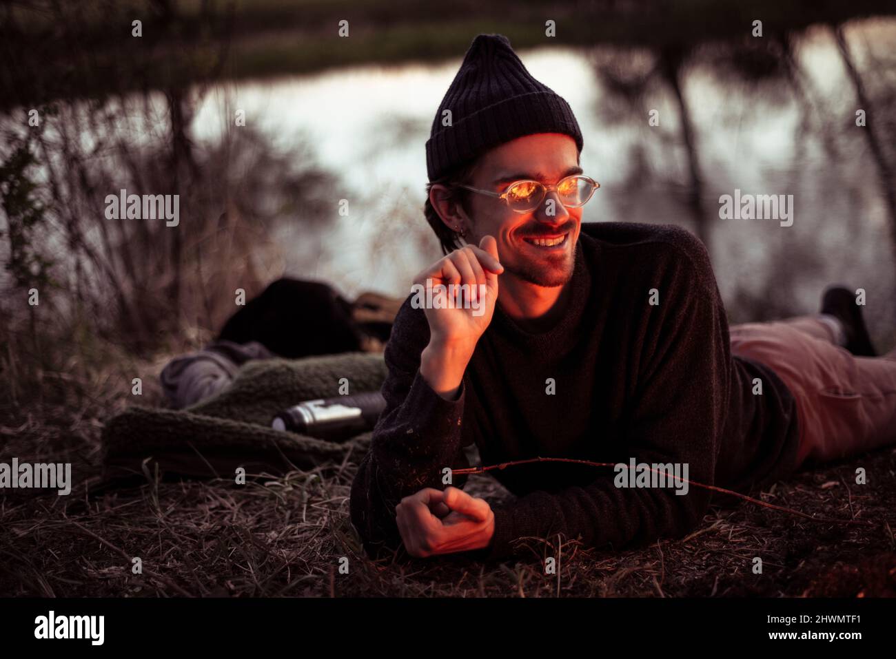 Junger alternativer Mann mit Brille entspannt sich durch Feuer und Wasser Stockfoto
