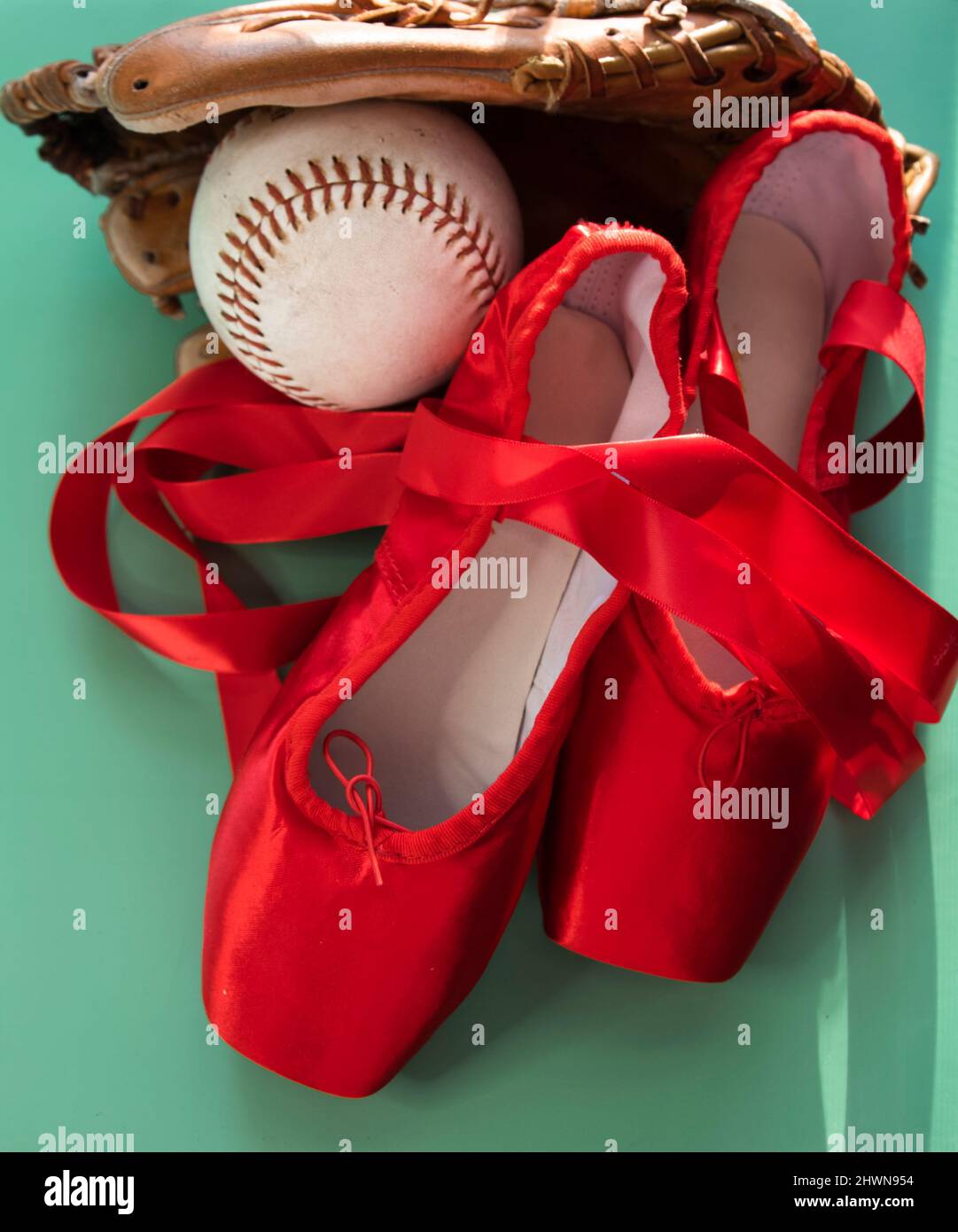 Leuchtend rote Ballet spitzenschuhe, gruppiert mit Softball und Handschuh. Vor blauem oder grünem Hintergrund. Stockfoto