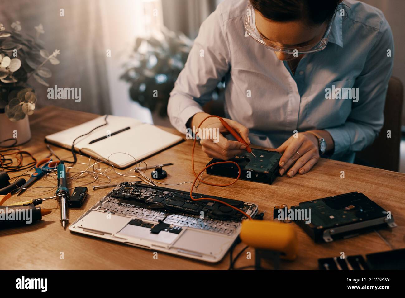 Shell hat diesen Laptop in kürzester Zeit einsatzbereit. Ausgeschnittene Aufnahme einer jungen Computertechnikerin, die in ihrer Werkstatt einen Laptop repariert. Stockfoto