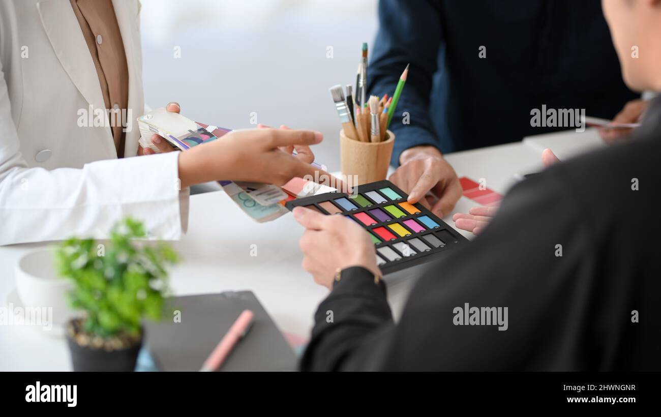 Das Team der Designer arbeitet im Büro zusammen, um über die Farbe für ihr Projekt zu diskutieren. Stockfoto