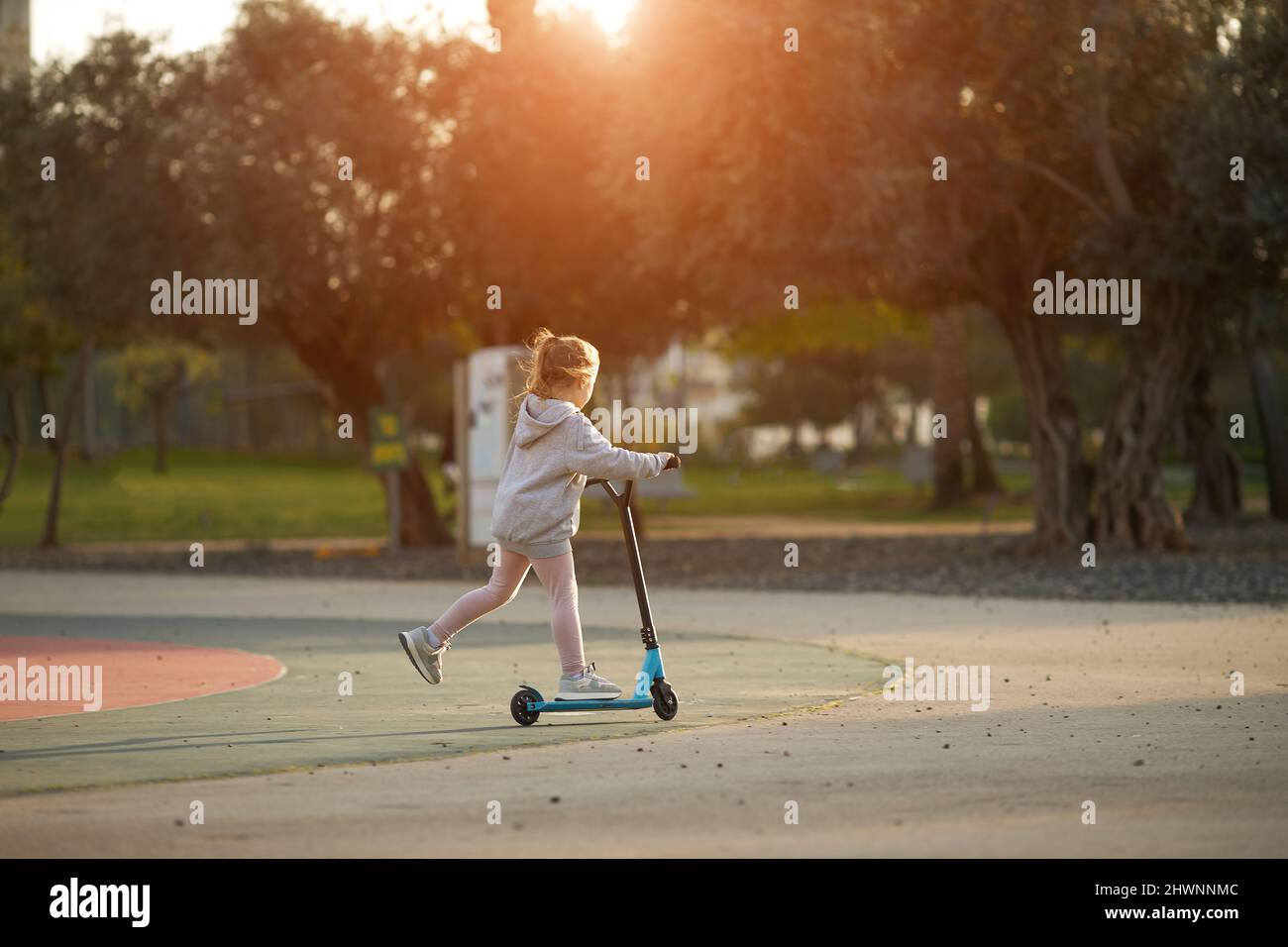 Kleine schöne Mädchen reitet einen Roller im Park Stockfoto