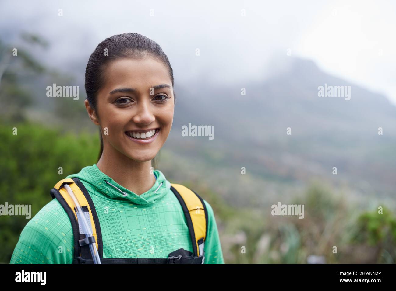 Sie liebt Trailrunning. Eine schöne junge Frau, die vor der Kulisse der malerischen Berge steht und eine Wanderung Unternehmen wird. Stockfoto