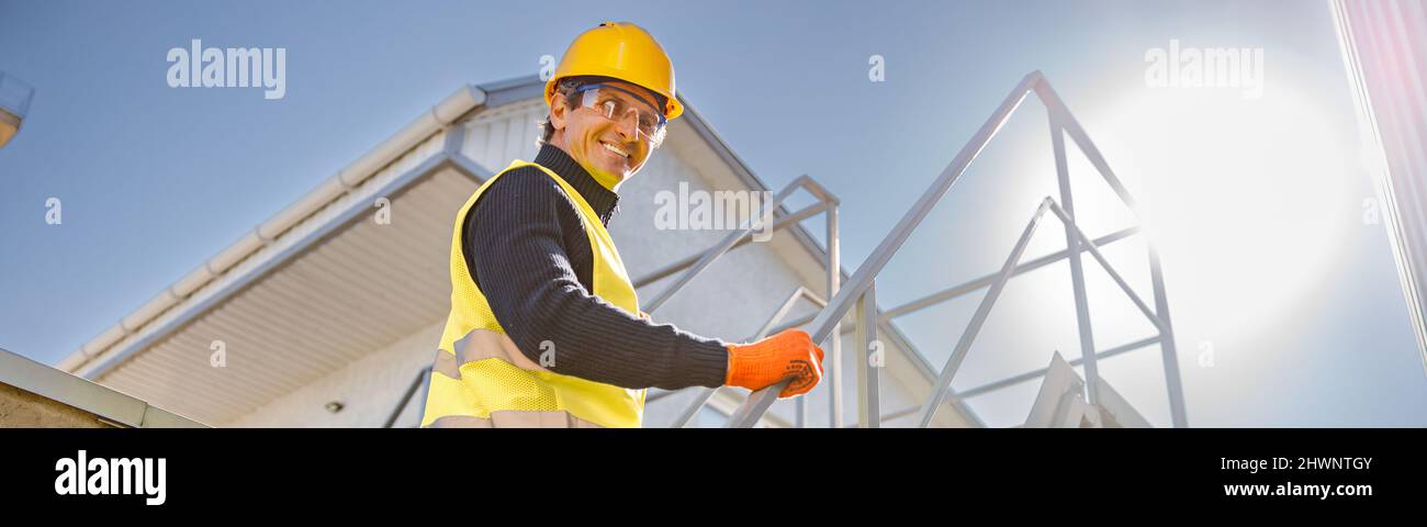 Fröhlicher männlicher Ingenieur, der in der Fabrik Treppen steigt Stockfoto