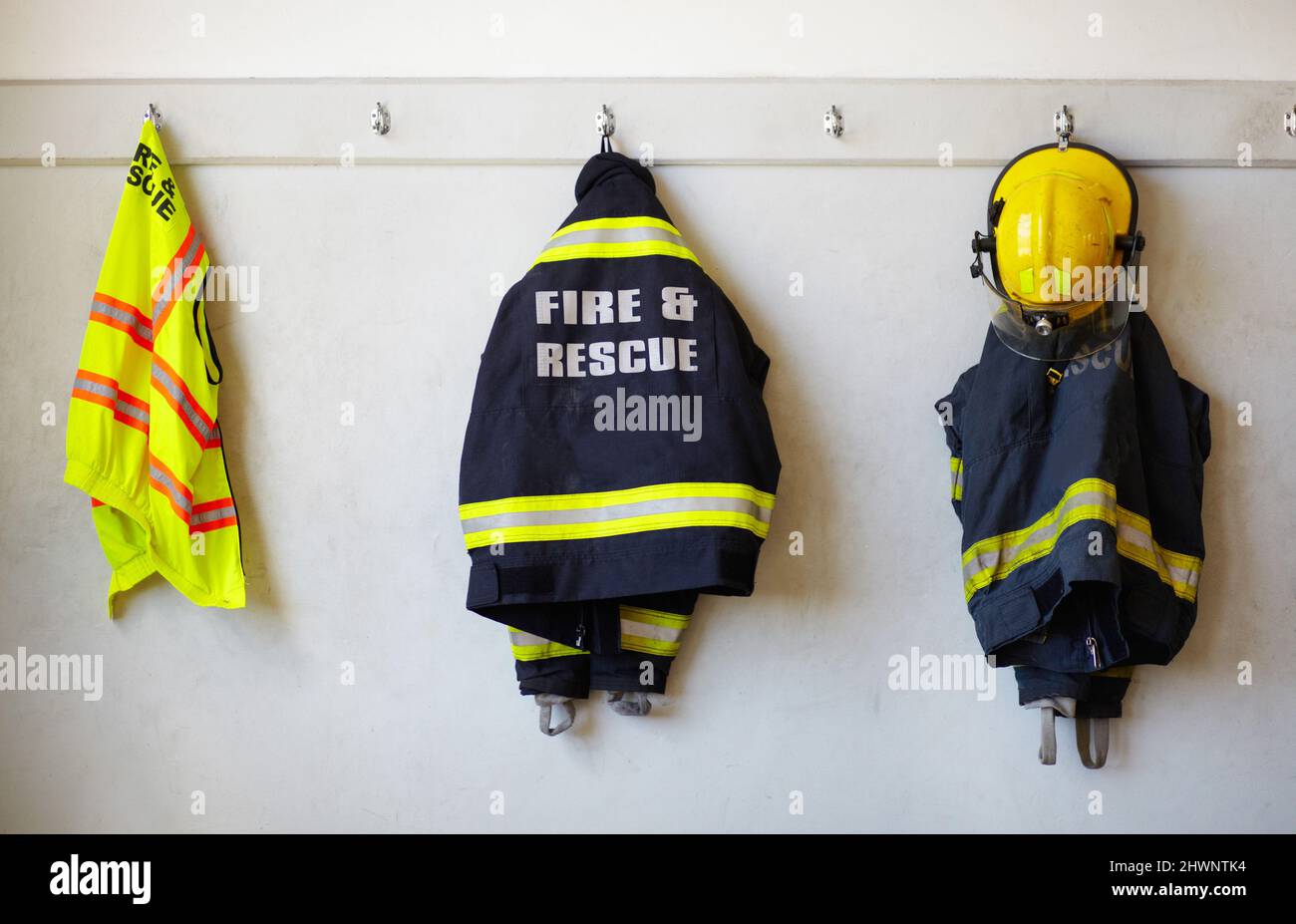 Es ist nicht die Uniform, die einen Helden macht. An einer Wand hängende Feuerwehrmänner-Kleidung. Stockfoto