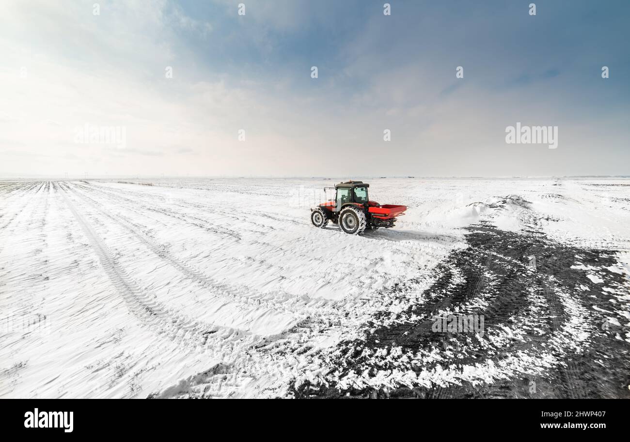 Bauer mit Traktor Aussaat Aussaat Kulturen auf landwirtschaftlichen Feldern im Winter - Schnee Stockfoto