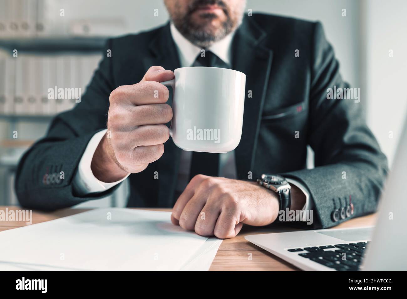 Eleganter, männlicher Geschäftsmann auf Kaffeepause im Büro, Geschäftsmann hält weiße Tasse heißen Kaffee, selektiver Fokus Stockfoto