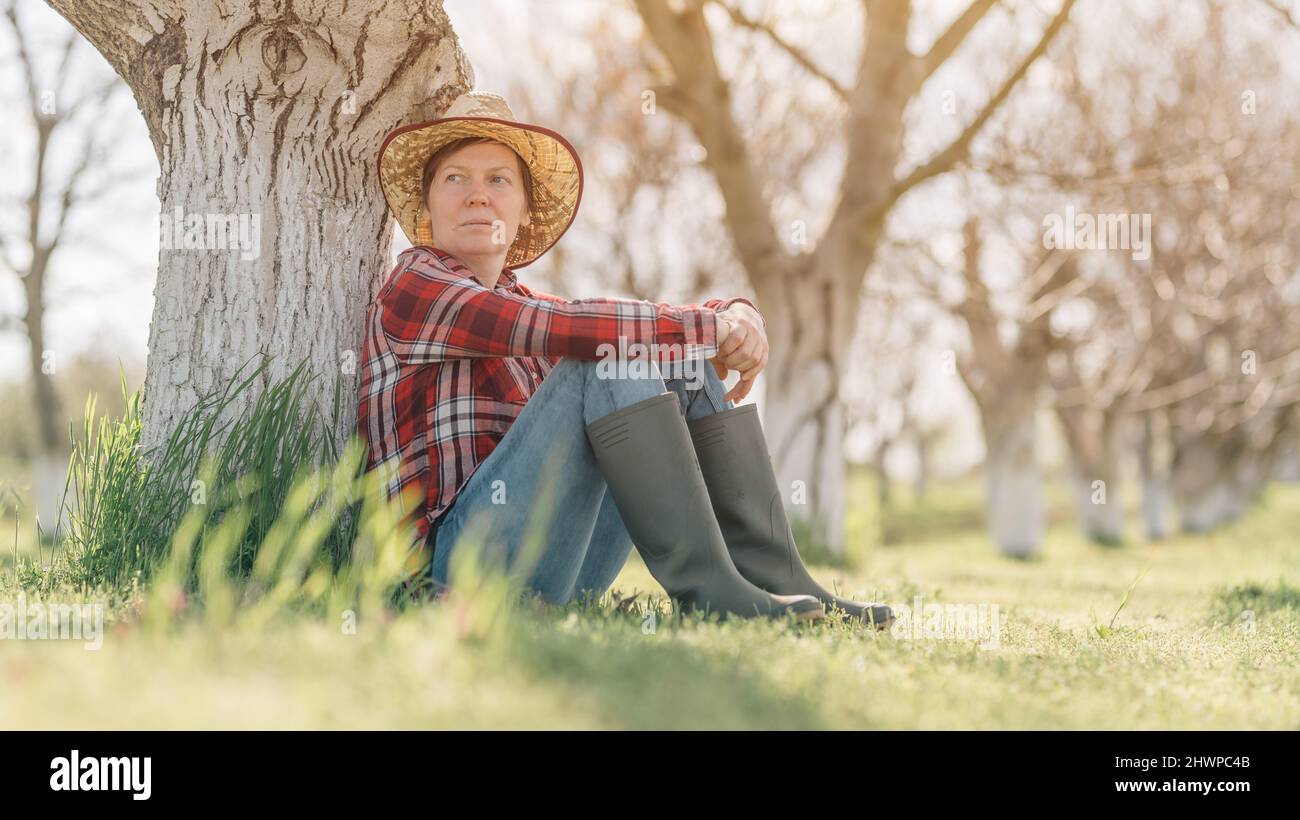 Bäuerin entspannt und ruht in Bio-Walnussplantage, sitzt unter dem Obstbaum im Frühjahr, selektive Fokus Stockfoto