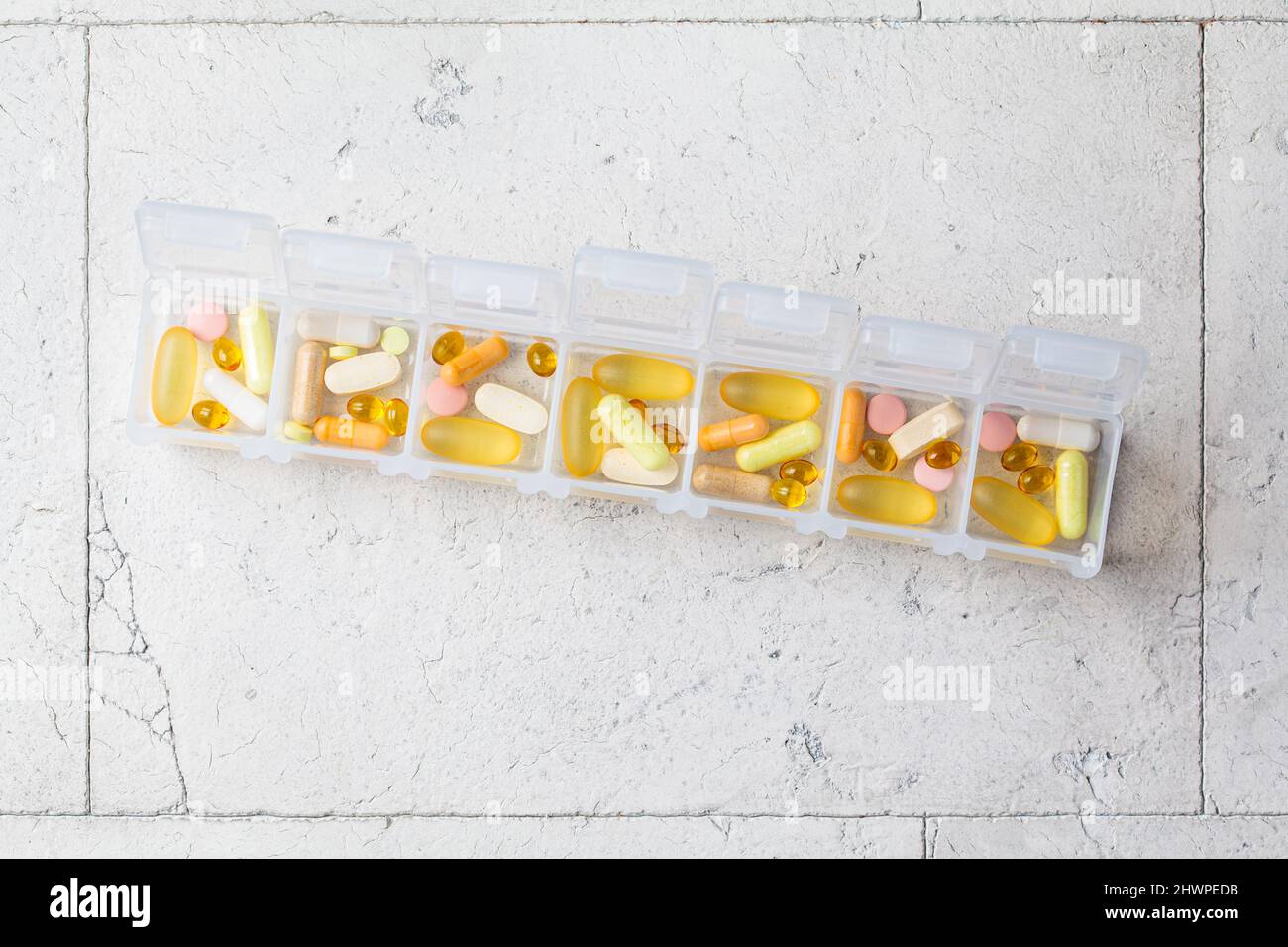 Pillen Box für die tägliche Einnahme von Vitaminen und Medikamenten, Draufsicht. Verschiedene Kapseln und Tabletten in einem weißen Behälter. Lifestyle für Schönheit und Gesundheit. Stockfoto