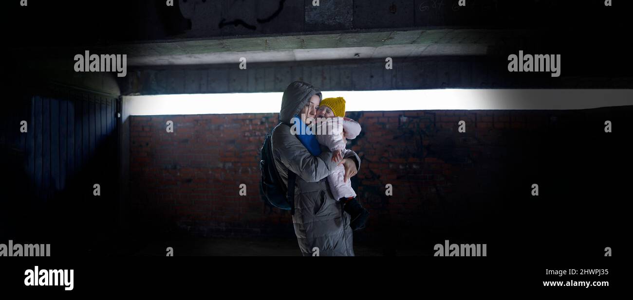 Erschöpfte Mutter hält ihr Kind in den Armen im Bombenschutzhaus Stockfoto