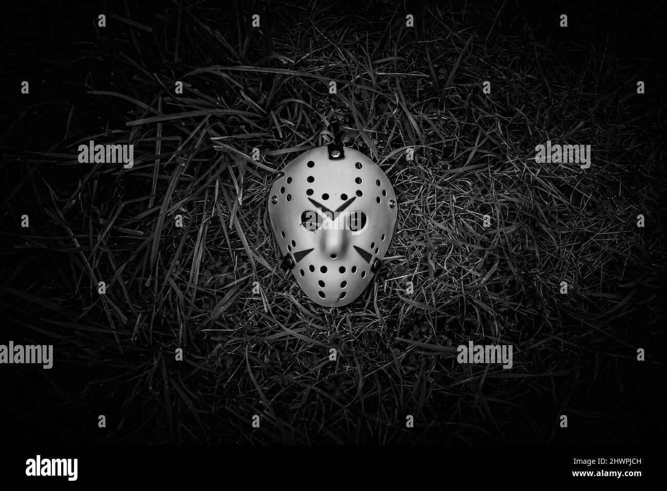 Gruselige weiße Hockey-Maske liegt in BW auf dem Boden Stockfoto