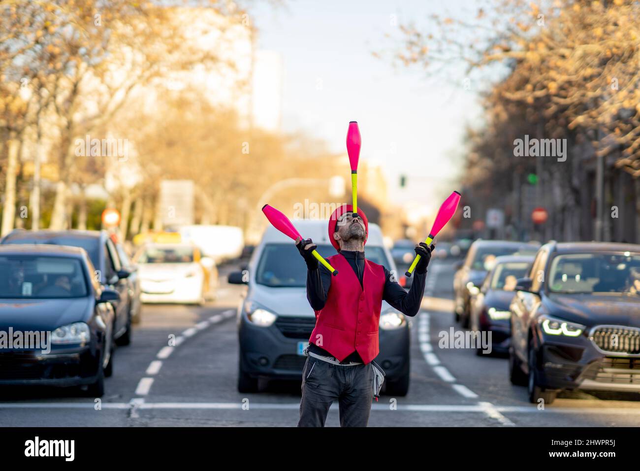 Künstler balanciert Jongliernadel auf der Nase vor Autos Stockfoto