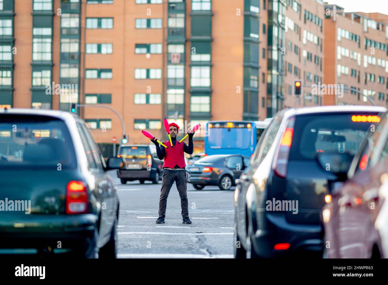 Solo-Performer jonglieren Pins umgeben von Autos auf der Straße in der Stadt Stockfoto