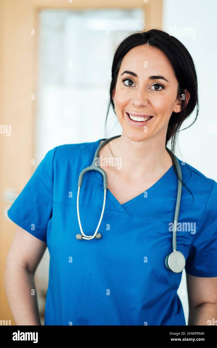 Glücklicher Arzt in blauen medizinischen Peelings im Krankenhaus Stockfoto