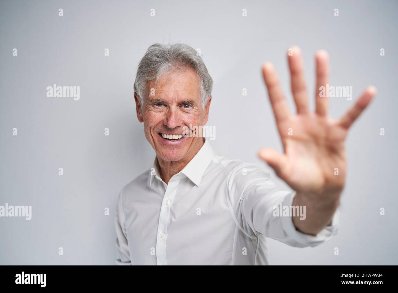 Glücklicher Geschäftsmann tut Stop-Geste vor weißem Hintergrund Stockfoto
