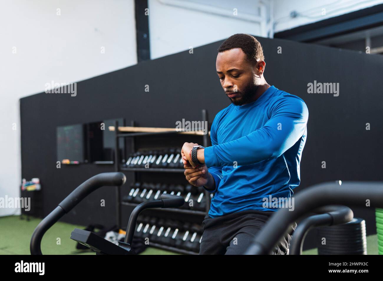 Athlet mit Fitness-Tracker sitzen auf airbike im Fitnessstudio Stockfoto