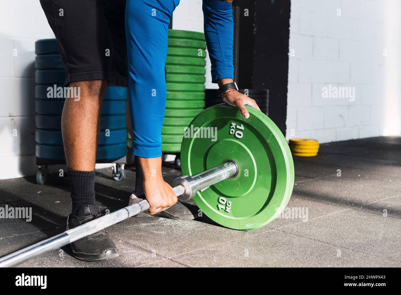 Sportler, der Hantelscheiben in die Langhantel legt, bevor er im Fitnessstudio trainiert Stockfoto