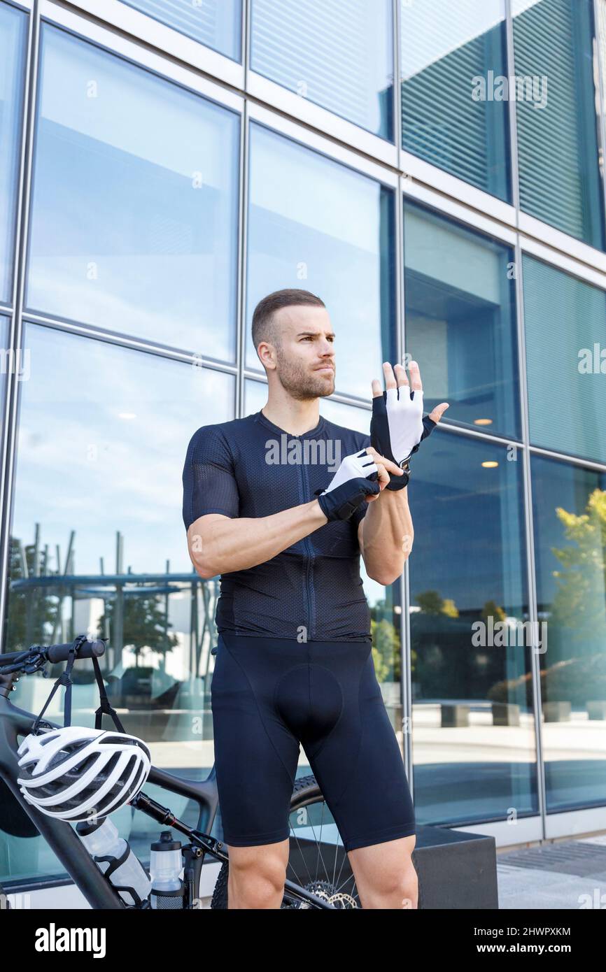 Junger Radfahrer mit Handschuhen vor dem Bürogebäude Stockfoto
