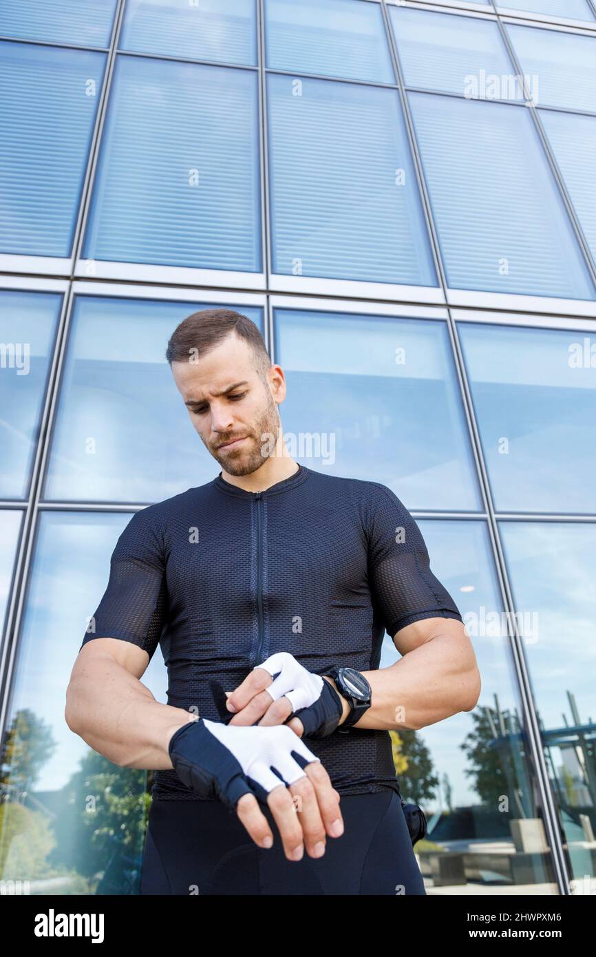 Junger Mann mit Fahrradhandschuh vor dem Bürogebäude Stockfoto