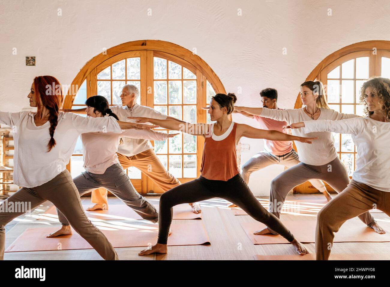 Yogalehrer, der den Schülern in der Klasse die Kriegerposition beibringt Stockfoto