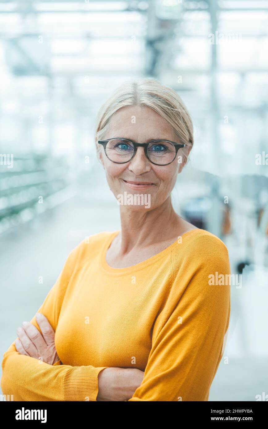 Lächelnde Geschäftsfrau mit Arme gekreuzt im Büro Stockfoto