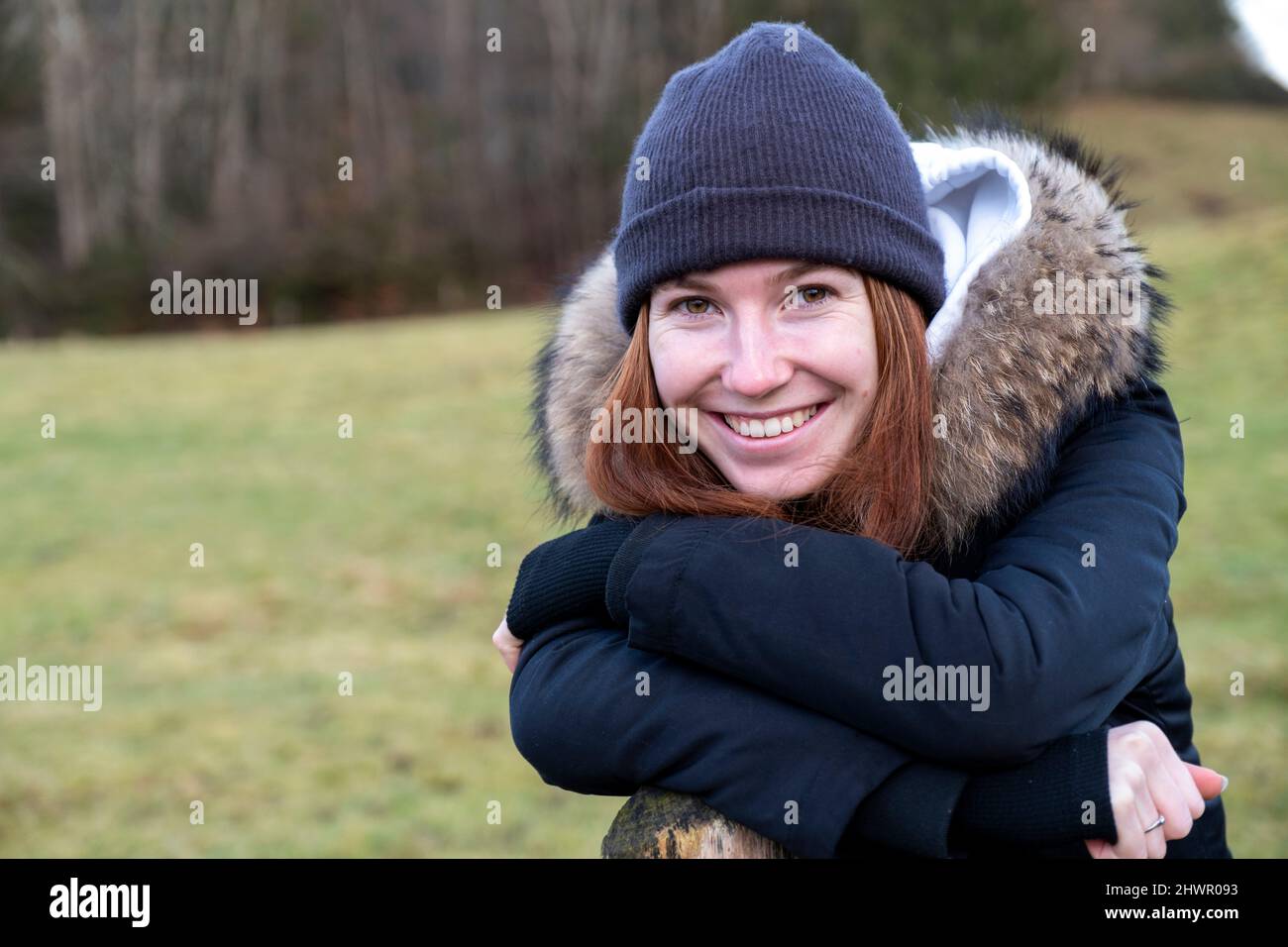 Lächelnde junge Frau mit warmer Kleidung und Strickmütze Stockfoto