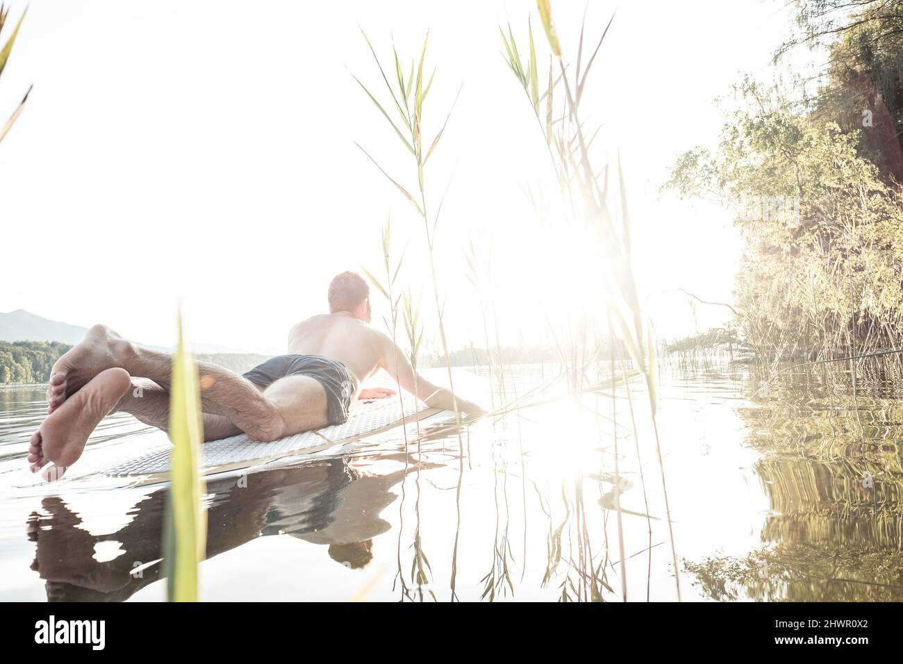 Mann genießt Urlaub auf dem Paddleboard am Staffelsee in Murrau, Bayern, Deutschland Stockfoto