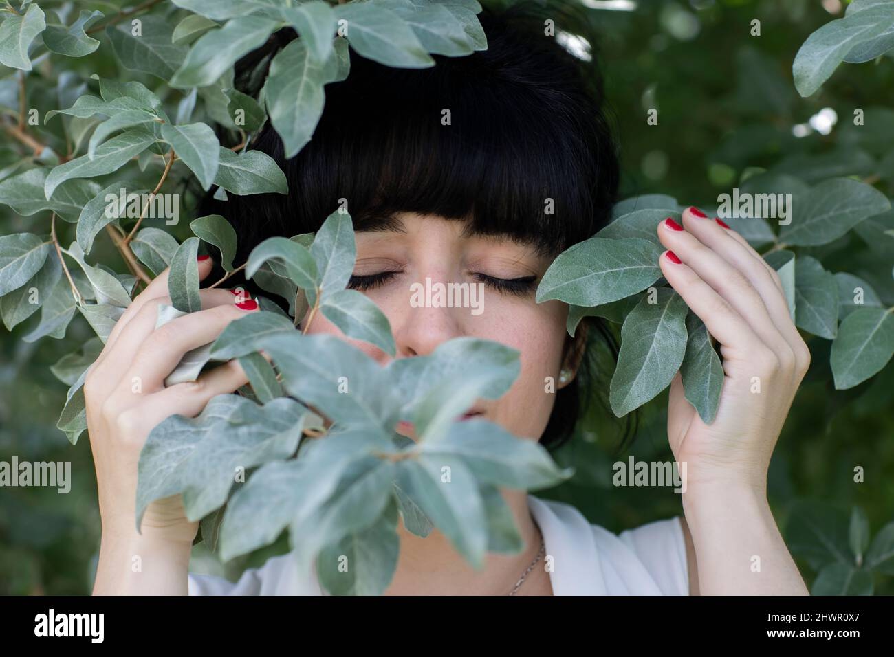Frau mit geschlossenen Augen inmitten von Blättern Stockfoto