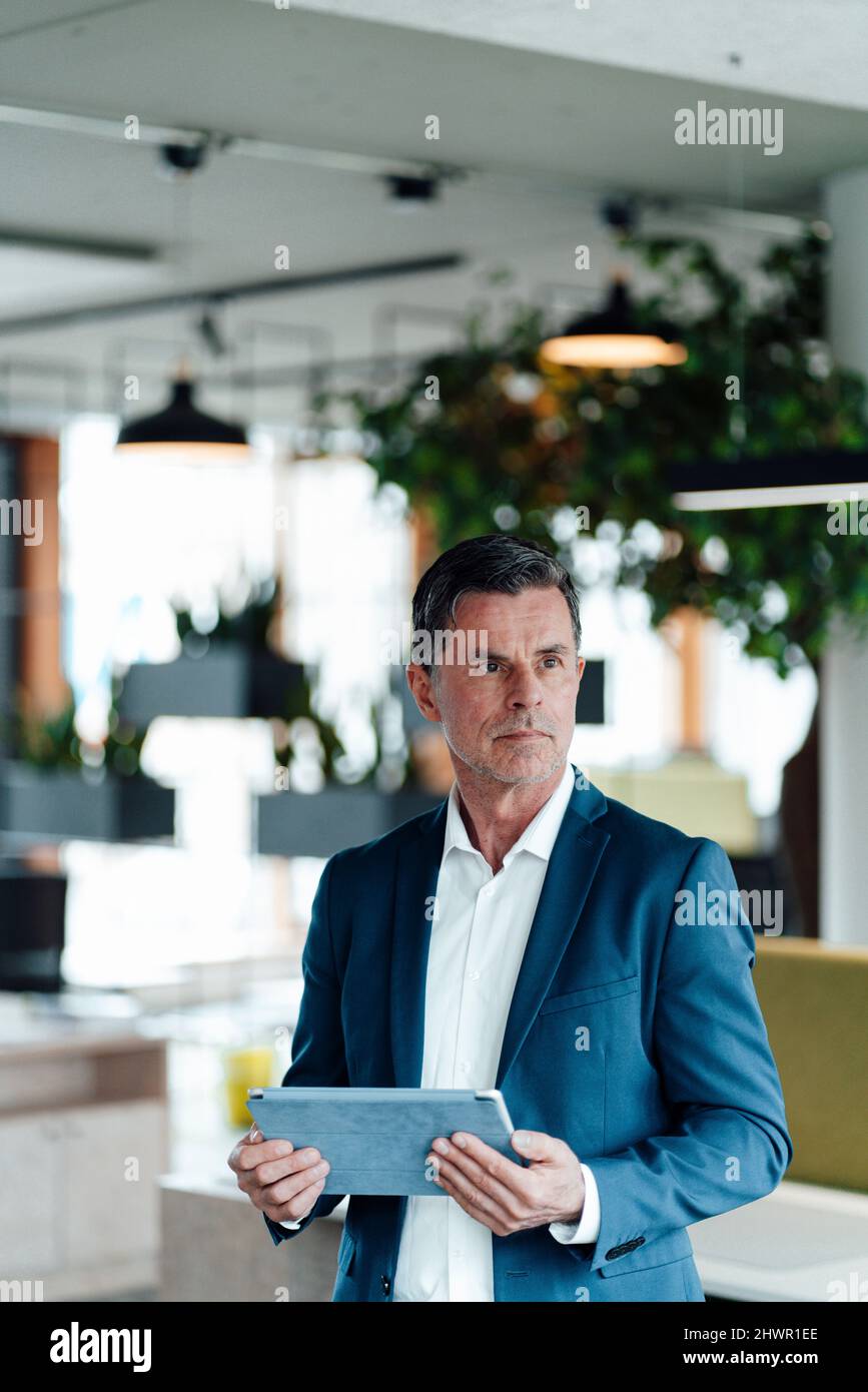 Durchdachter Geschäftsmann mit Tablet-PC im Büro Stockfoto