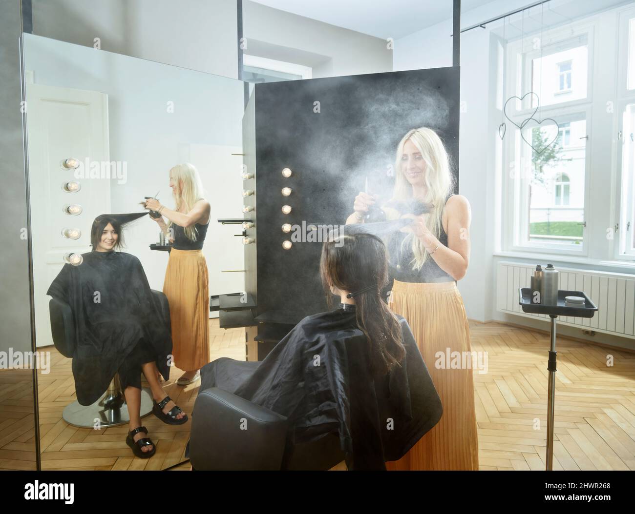Friseur sprühen Haarspray auf Frauenhaare im Salon Stockfoto