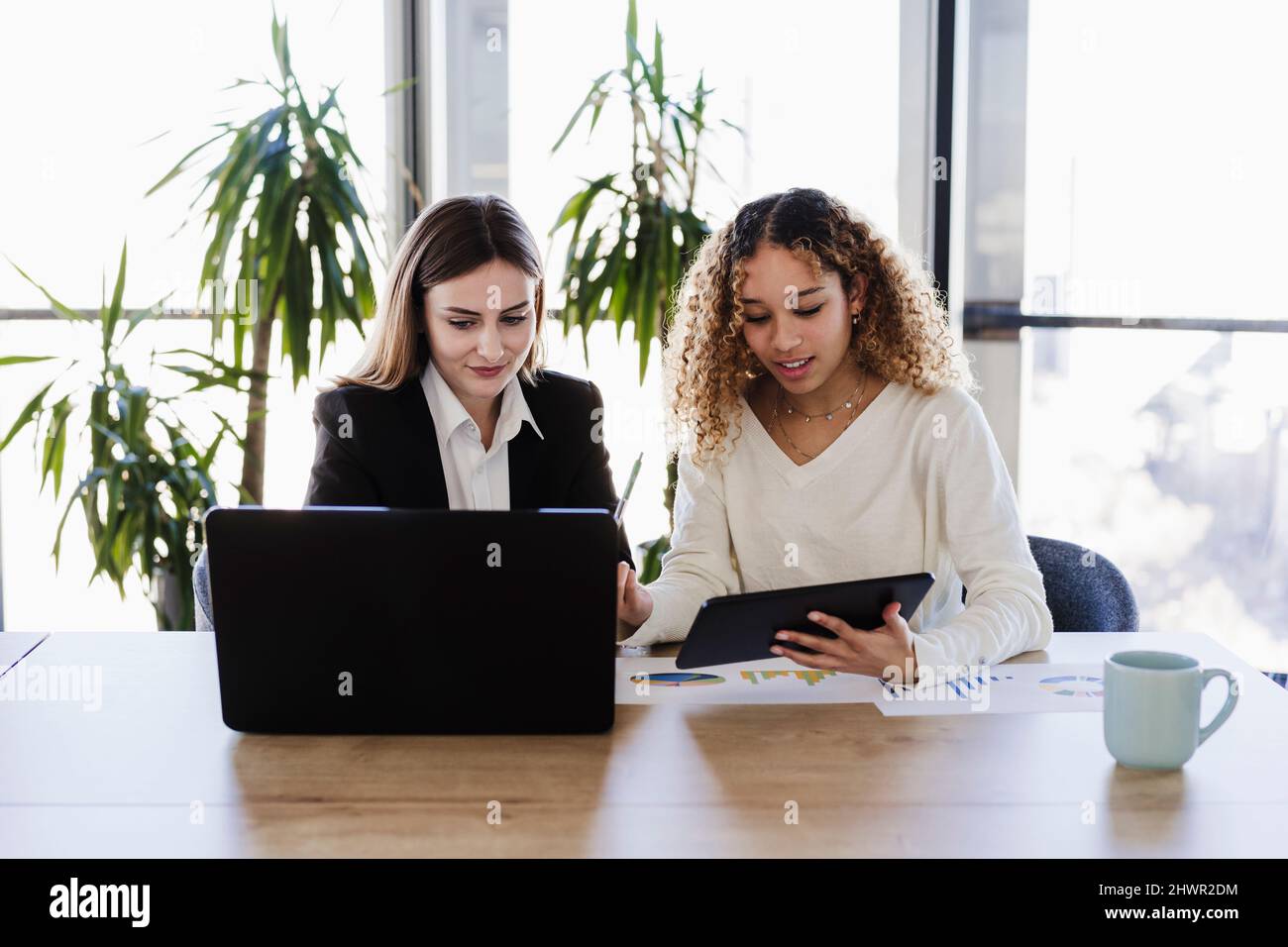 Multiethnische Geschäftskollegen, die im Coworking Office mit drahtlosen Technologien arbeiten Stockfoto