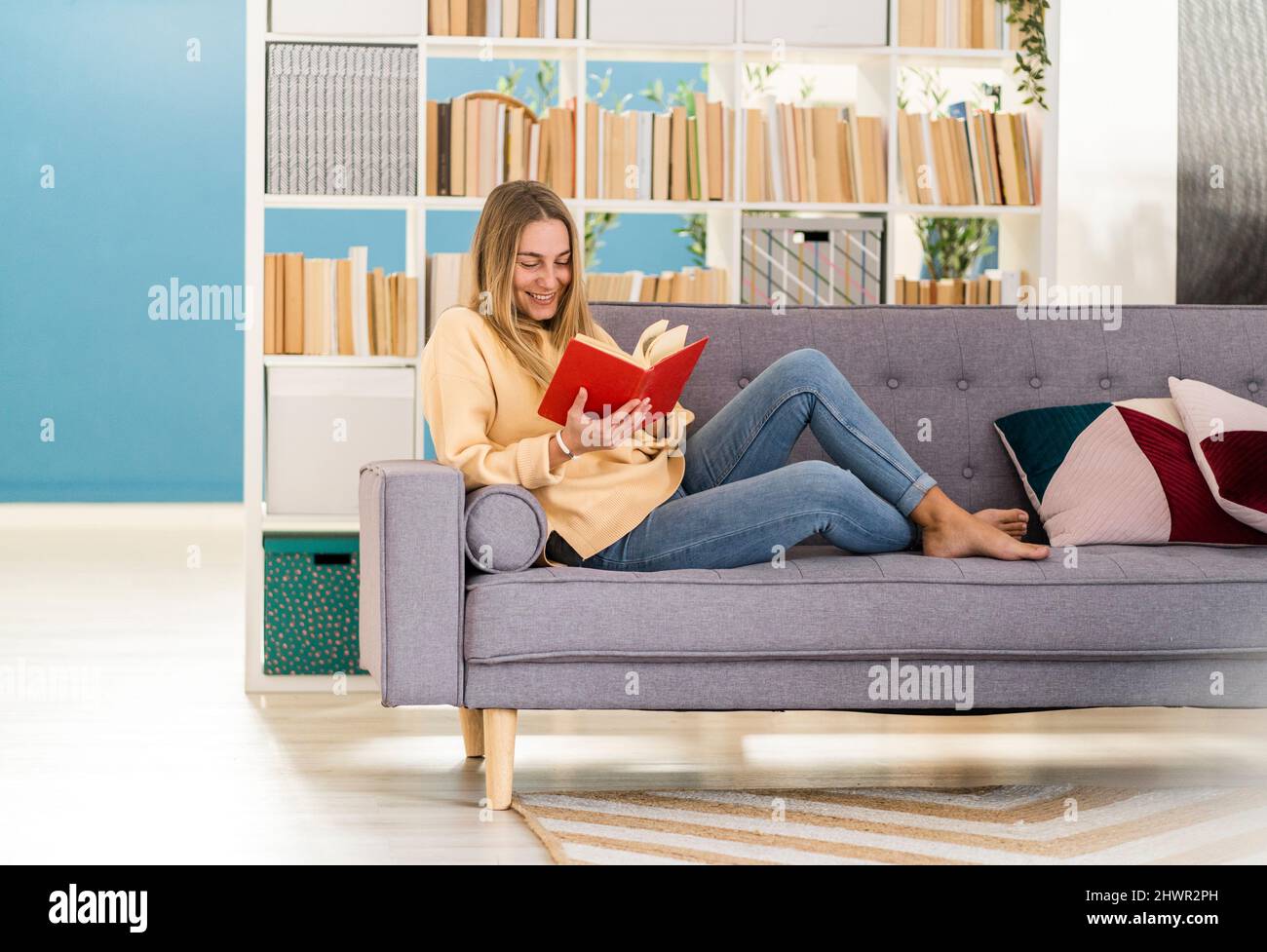 Junge Frau mit Buch auf dem Sofa zu Hause Stockfoto