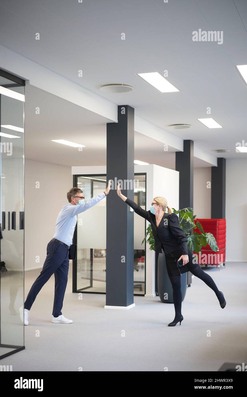 Geschäftsmann und Geschäftsfrau geben High-Five und Aufrechterhaltung der sozialen Distanz im Büro Stockfoto