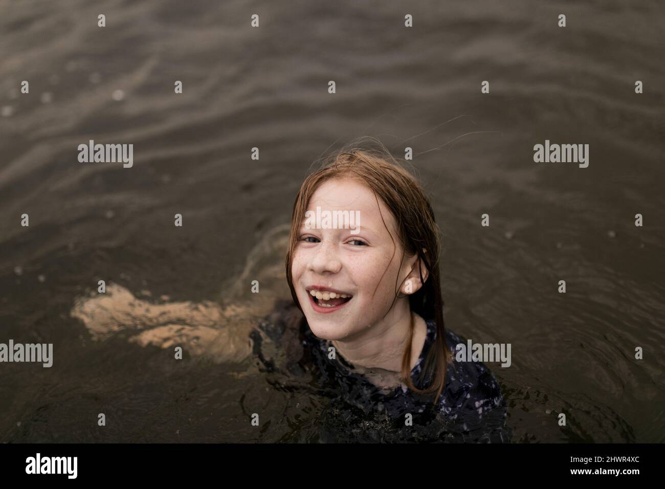 Glückliches Mädchen mit braunen Haaren, die im Wasser spielen Stockfoto
