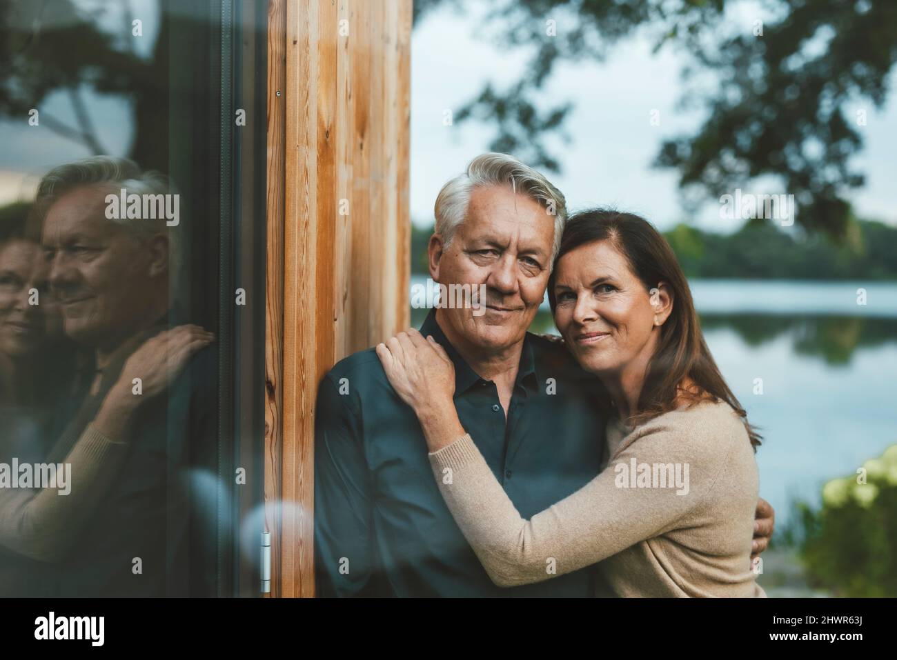 Lächelndes Paar, das an einer Glaswand steht Stockfoto