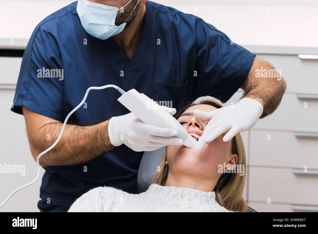 Zahnarzt, der die Zähne des Patienten mit einem intraoralen Scanner in der Klinik untersucht Stockfoto
