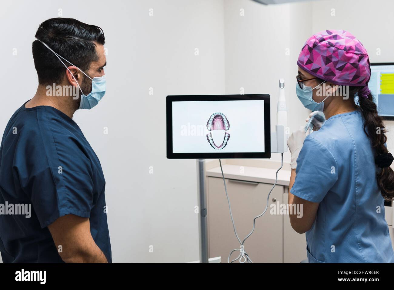 Zahnarzt diskutiert mit Kollegen über intraoralen Scannerbildschirm in der Klinik Stockfoto