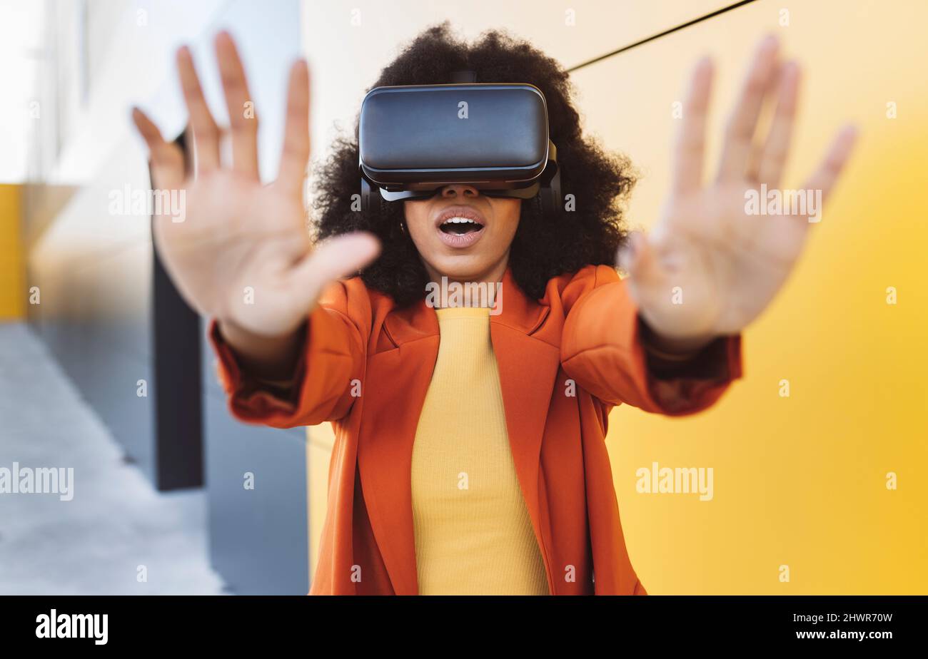 Frau mit VR-Brille tut Stop-Geste in der Nähe der Wand Stockfoto