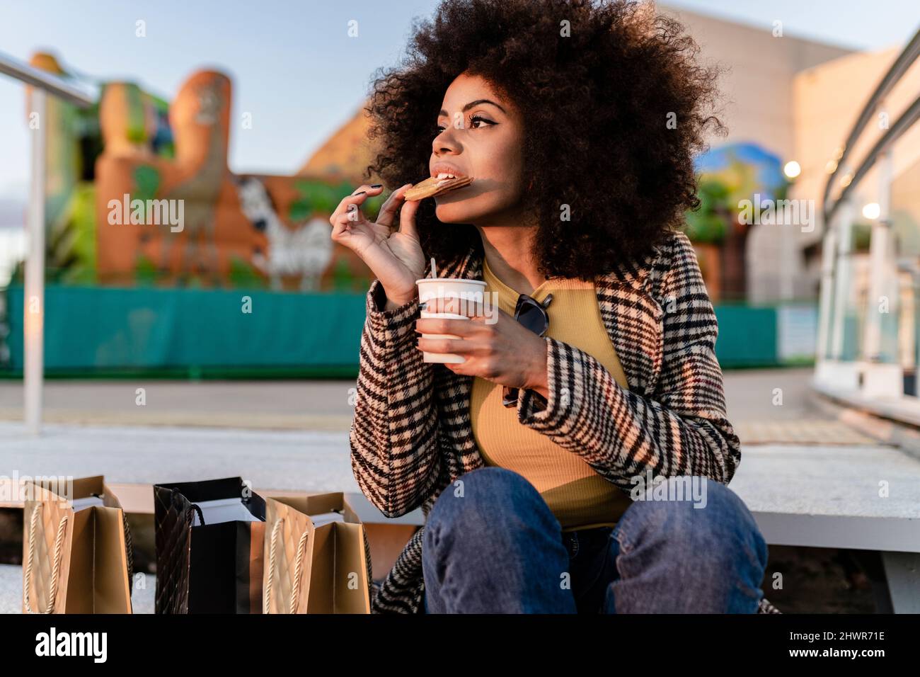 Frau, die einen Snack isst, sitzt auf der Stufe Stockfoto